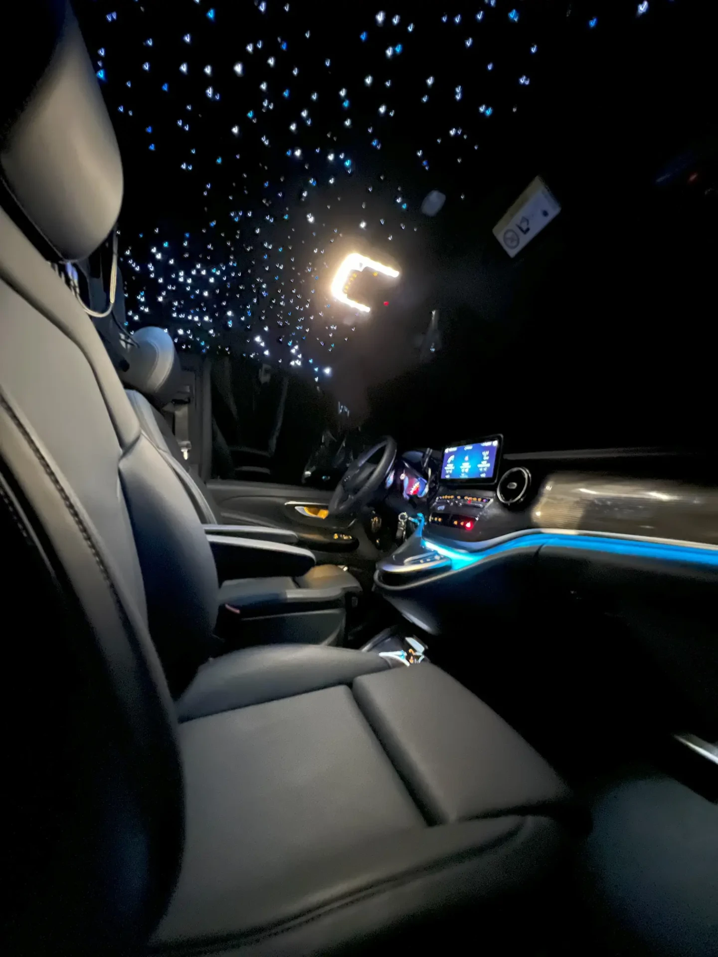 Habitacle avant de la Mercedes Classe V DayNight Drive avec ciel étoilé et éclairage d'ambiance bleu